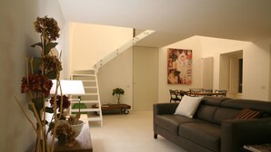 A modern living room with a sofa, a coffee table, and a staircase leading to another level. - Le Tre Vie Apartment & Room (Matera)