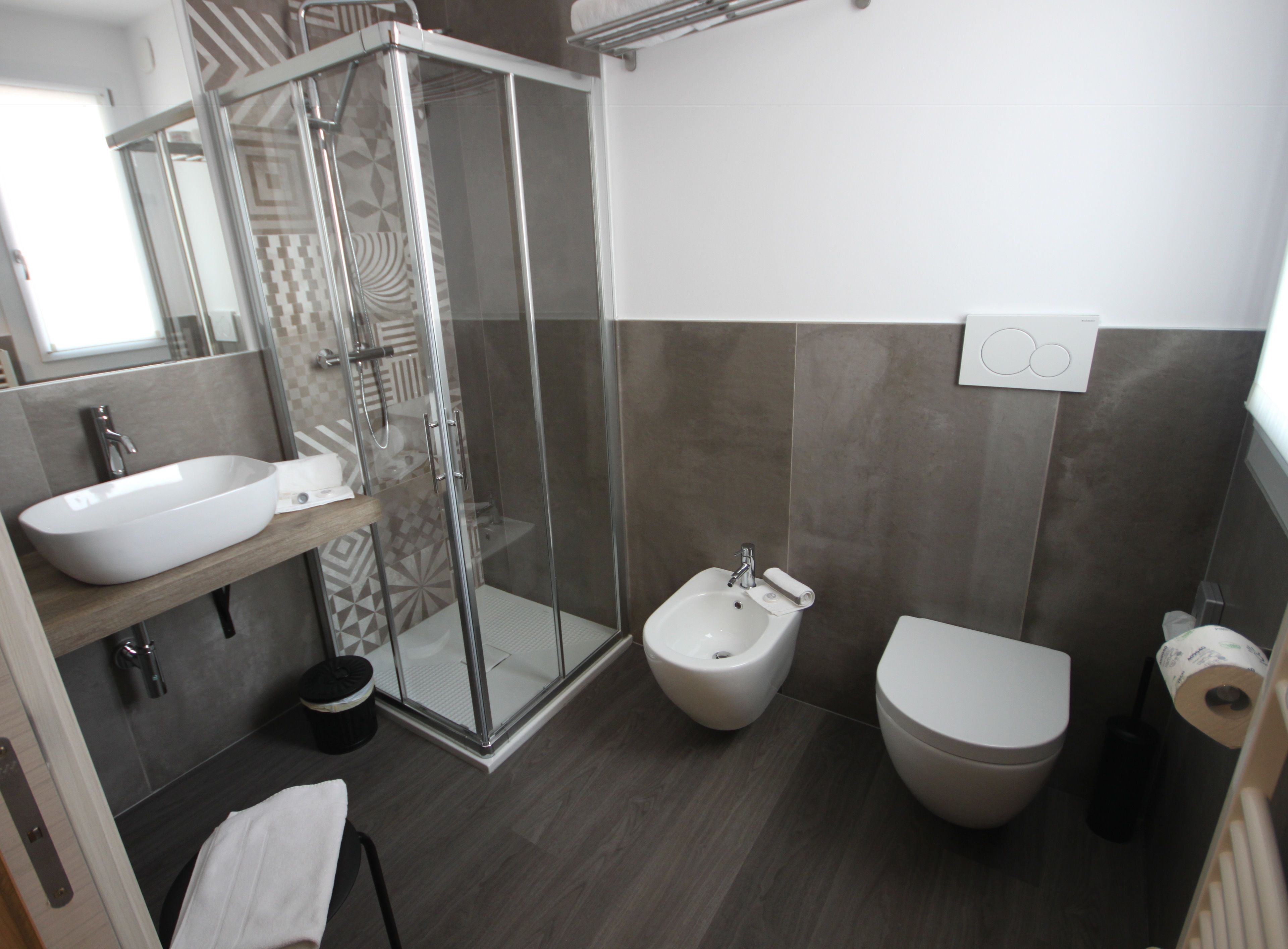 Un bagno moderno con doccia vetro, lavabo, bidet e WC.