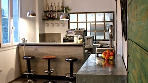 A modern kitchen with a bar area, bar stools, and a large window providing natural light. - Pove 2.4 Hotel (Pove del Grappa)