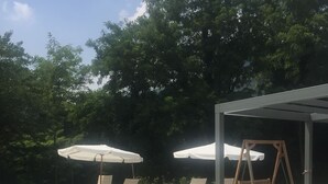 A swimming pool with lounge chairs and umbrellas, surrounded by trees. - Pove 2.4 Hotel (Pove del Grappa)