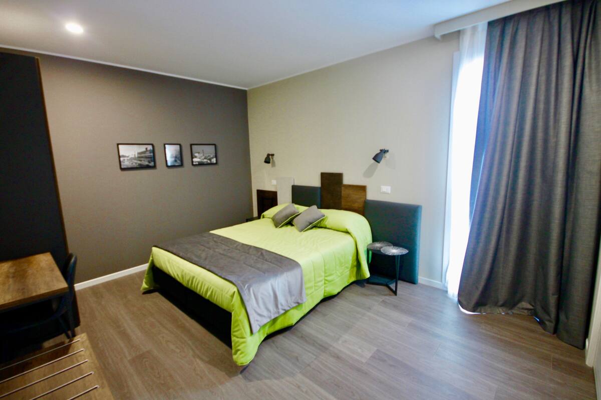 A modern bedroom with a bed, bedside tables, and a desk.