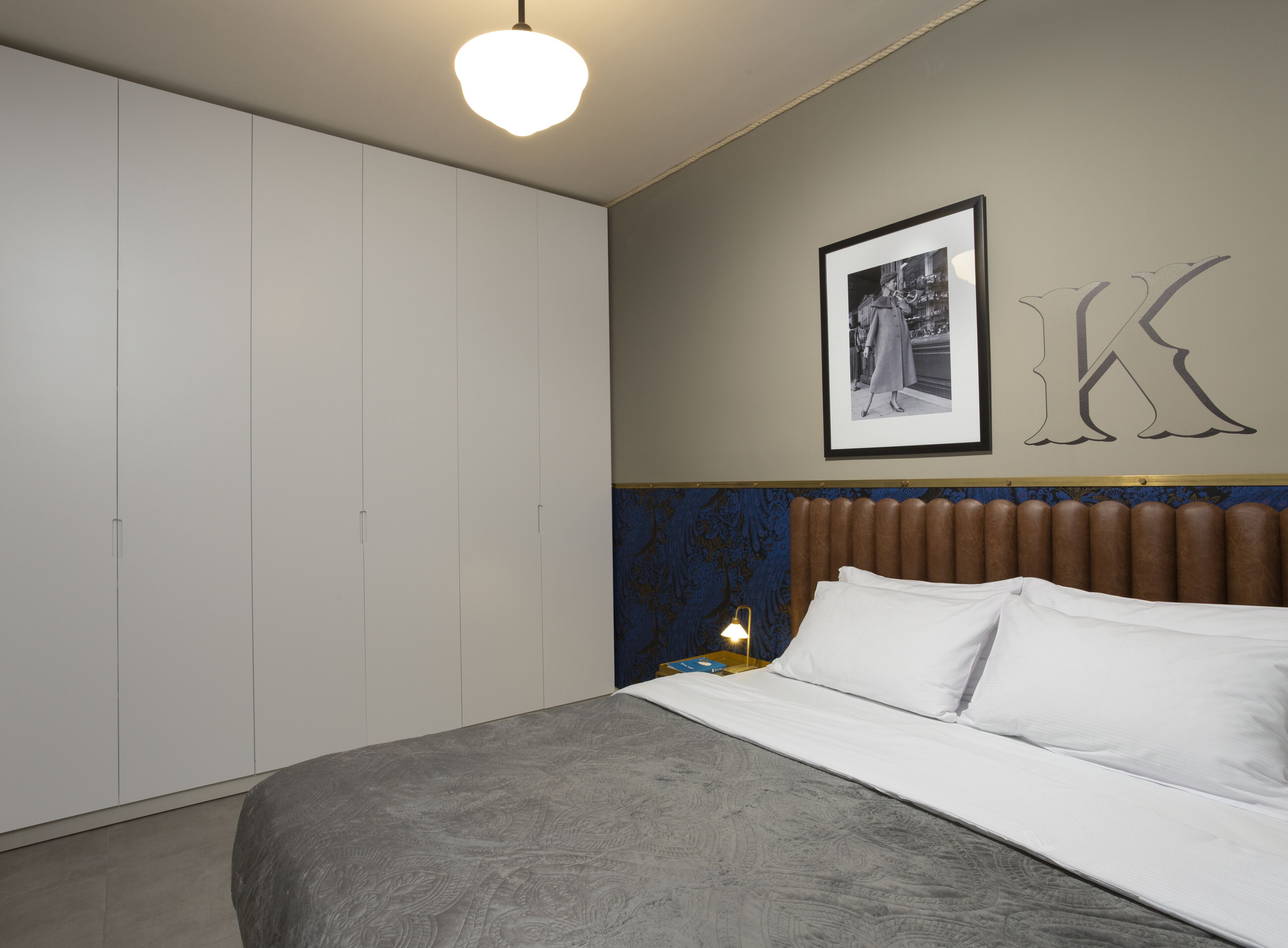 A bedroom with a bed, a wardrobe, a framed picture, and a wall decoration.