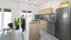 A modern kitchen with a central island, stainless steel appliances, wooden cabinets, and pendant lighting. - Mr. Katinsky - By TLV2GO (Tel Aviv)