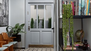 A modern interior with a white door, a bookshelf with books, a globe, and a potted plant. - Mr. Katinsky - By TLV2GO (Tel Aviv)
