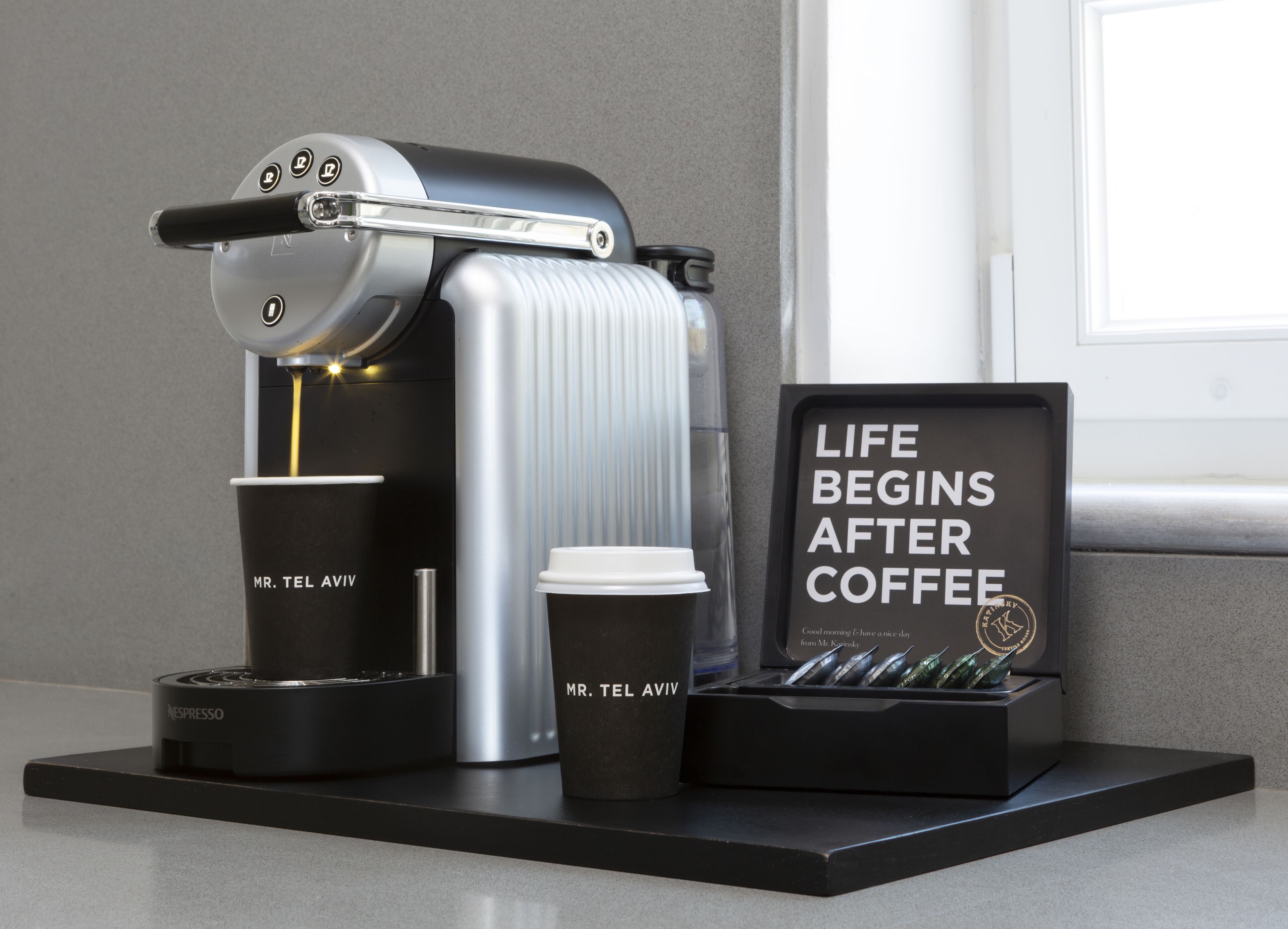 A coffee machine with a cup and a sign that reads "Life Begins After Coffee."