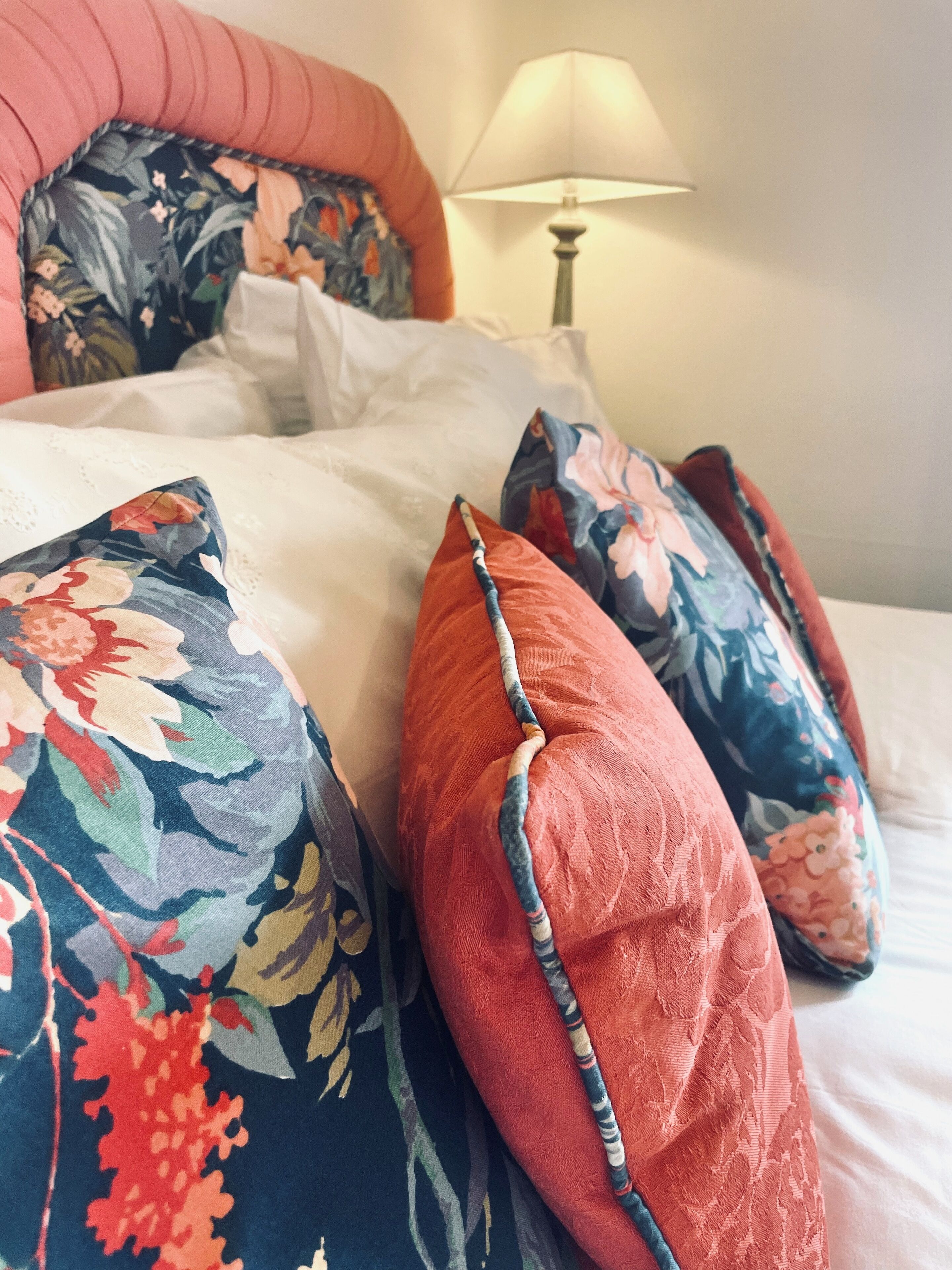 Una cama con almohadas estampadas con flores y una colcha blanca.