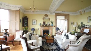 Un salon traditionnel avec une cheminée, des meubles blancs et un tapis à motifs.