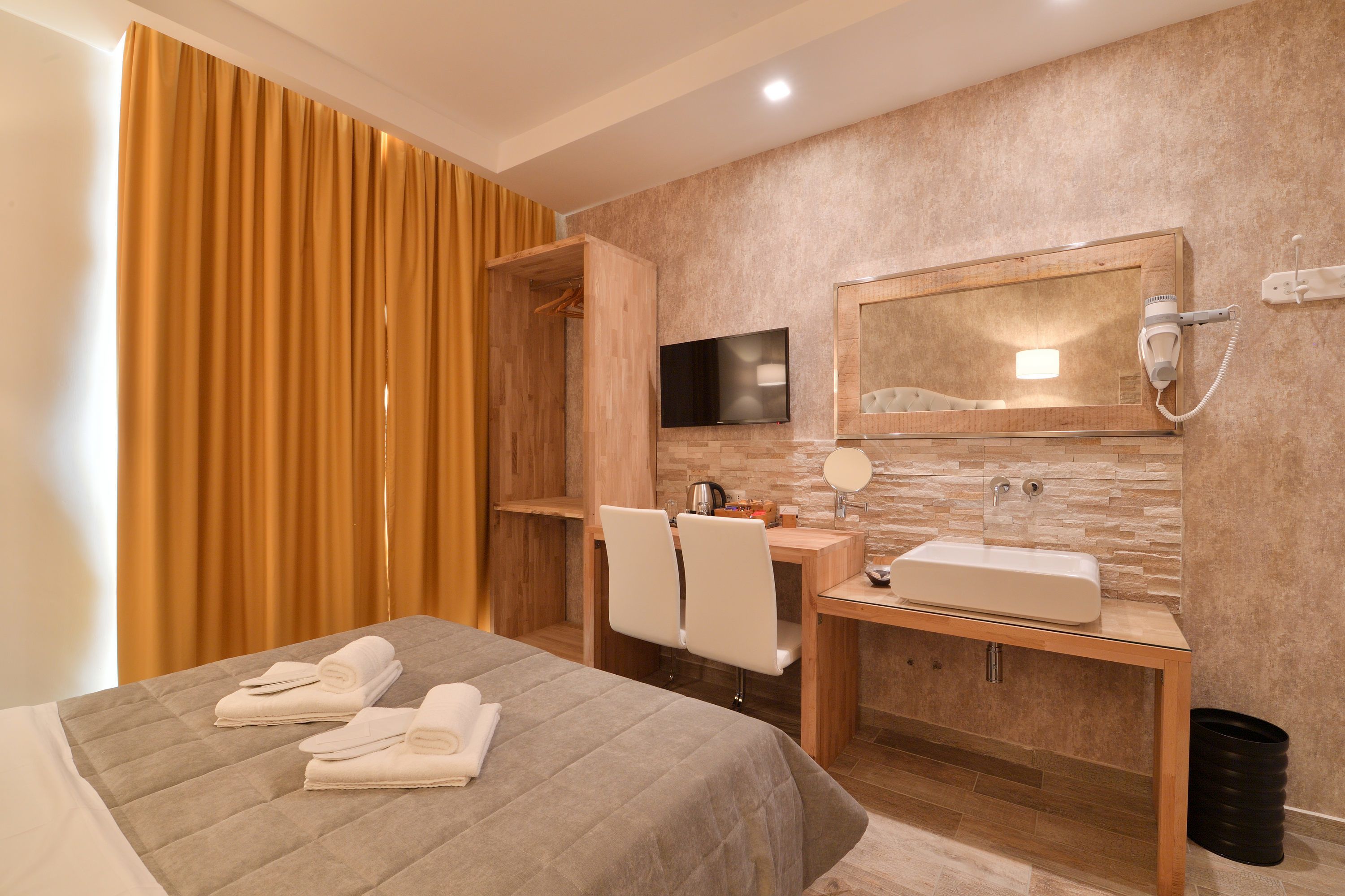 Une chambre d’hôtel avec un lit, un bureau doté d’un miroir, un lavabo et une télévision.