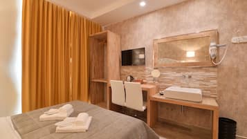Une chambre d’hôtel avec un lit, un bureau doté d’un miroir, un lavabo et une télévision.