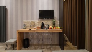 A modern kitchen with a wooden countertop, a flat-screen TV mounted on the wall, and a fruit bowl on the counter.