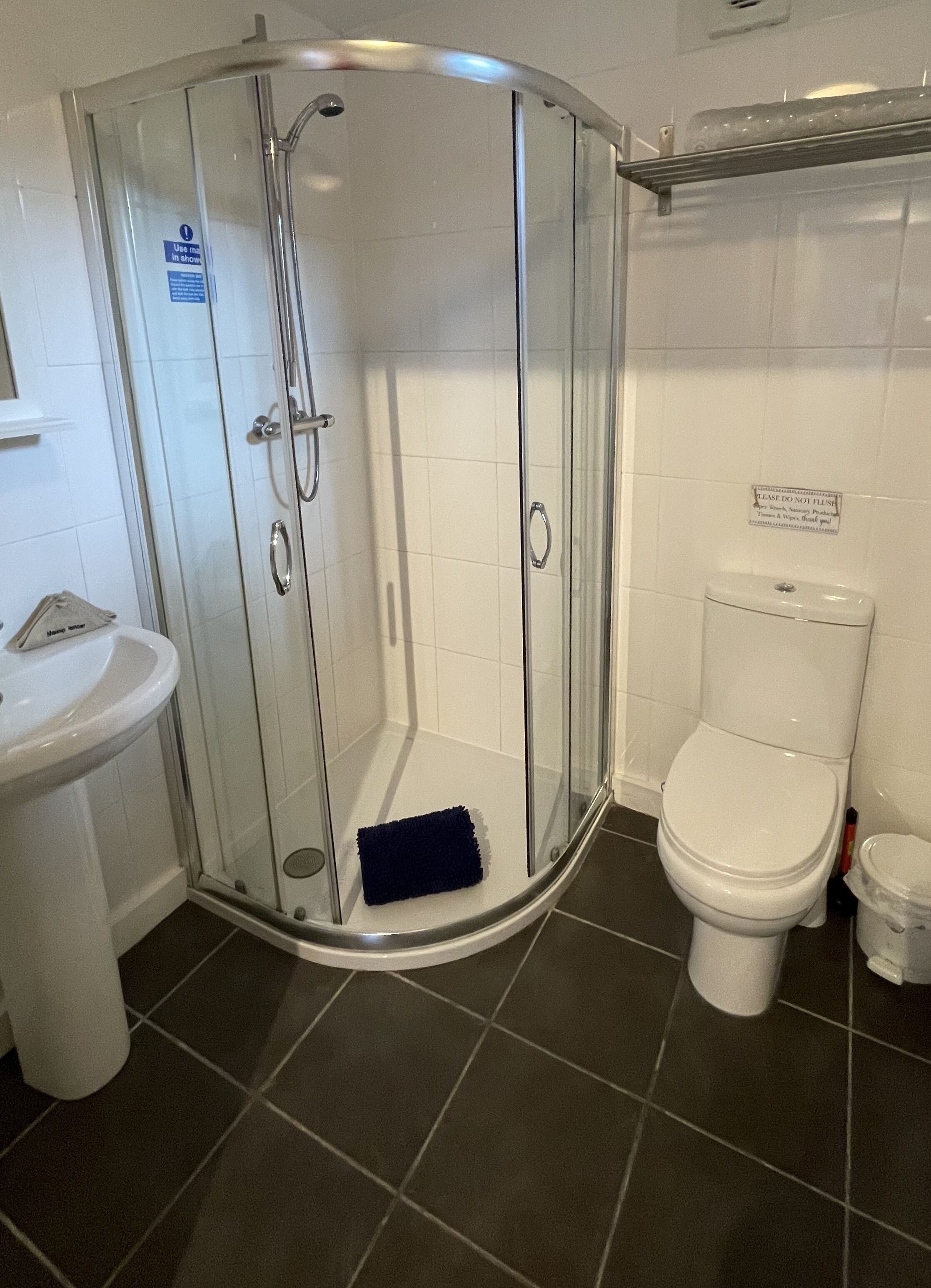 A bathroom with a glass-enclosed shower, a toilet, and a sink.