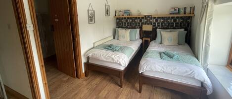 Ein Schlafzimmer mit zwei hölzernen Betten, einem Holzschrank und einem Regal mit Büchern und Dekoration.