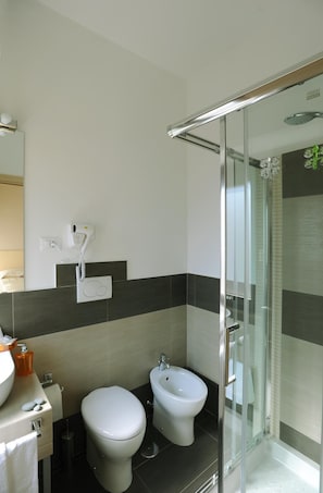 Uma casa de banho moderna com sanita, bidé e cabine de duche em vidro.