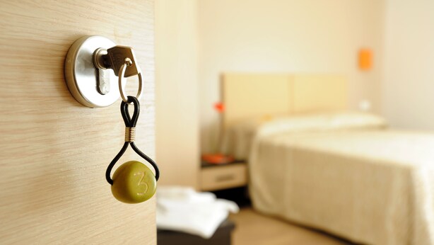 Habitación de hotel con cama, mesita de noche y cerradura en la pared.