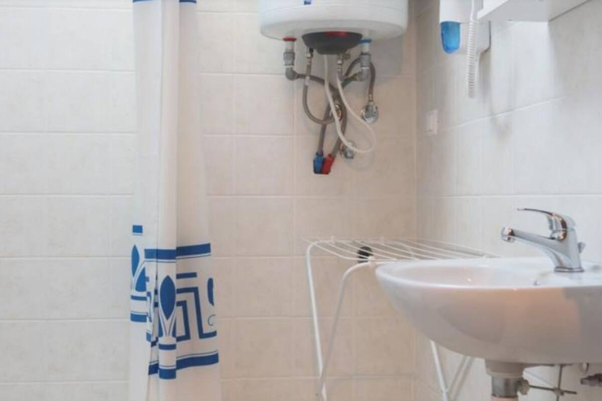 A bathroom with a shower, a sink, and a towel rack.