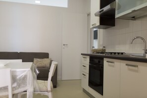 A modern kitchen with white cabinets, a black oven, and a stainless steel faucet. - Residence Le Vie del Centro (Matera)