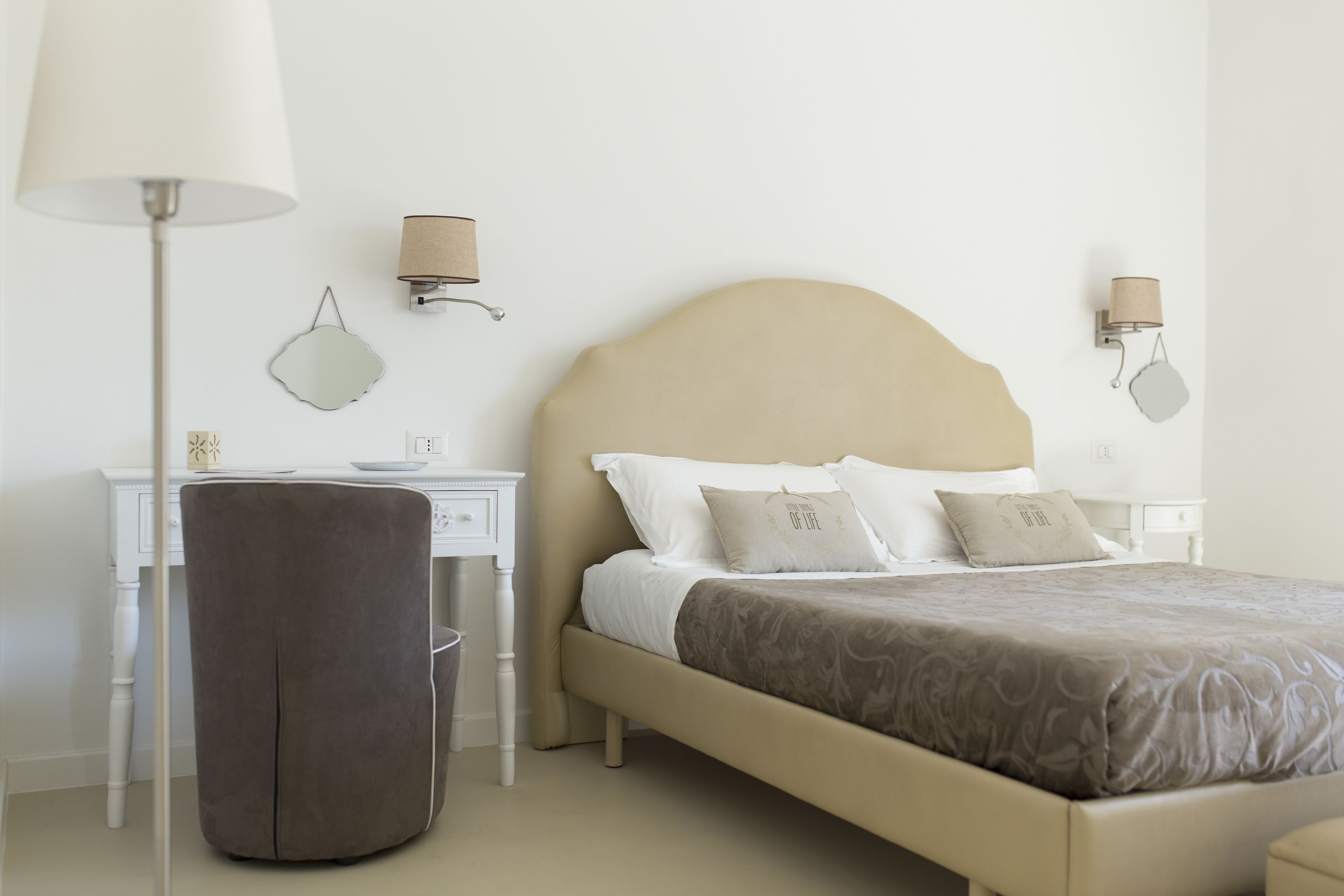 A neatly arranged bedroom with a bed, bedside tables, a desk, and a chair.