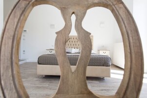 Una camera da letto con testiera trapuntata, un letto con copriletto grigio e un comodino con una lampada.