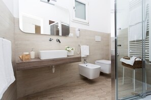 A modern bathroom with a large sink, a bidet, a toilet, and a glass shower enclosure. - Residence Le Vie del Centro (Matera)