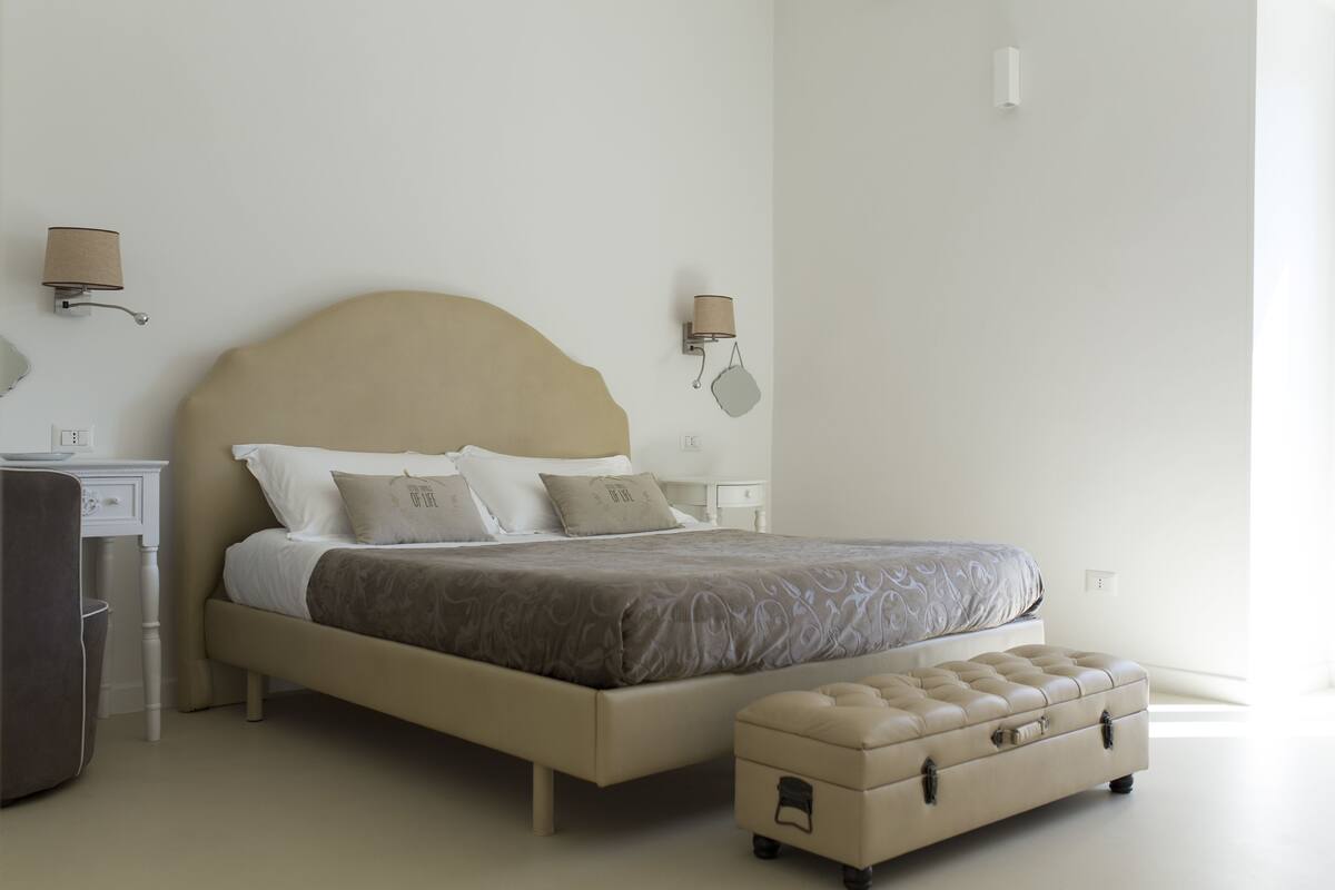 A bedroom with a bed, bedside tables, a nightstand, a lamp, and a suitcase.