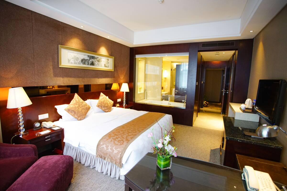 Une chambre d’hôtel avec un grand lit, des lampes de chevet, une table de chevet, un bureau avec un téléphone et un miroir.