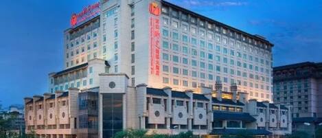 A multi-story hotel with a prominent sign at the top, large windows, and a modern architectural style.