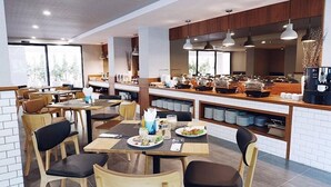 A modern restaurant with wooden tables and chairs, a buffet area with various food items, and a coffee machine. - Hotel MAYU Chiang Mai (Chiang Mai)