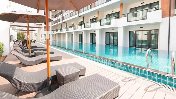 A modern hotel with a rooftop pool area featuring lounge chairs and umbrellas. - Hotel MAYU Chiang Mai (Chiang Mai)