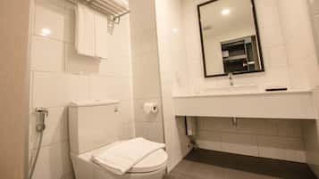 Un baño moderno con inodoro, toallero, lavamanos y espejo.