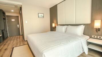 Habitación de hotel con una cama grande, mesitas de noche, cabecero y un cuadro en la pared.