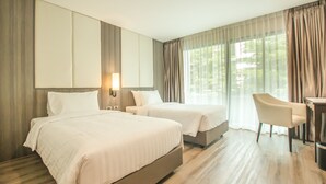 A hotel room with two beds, a desk, and a chair.