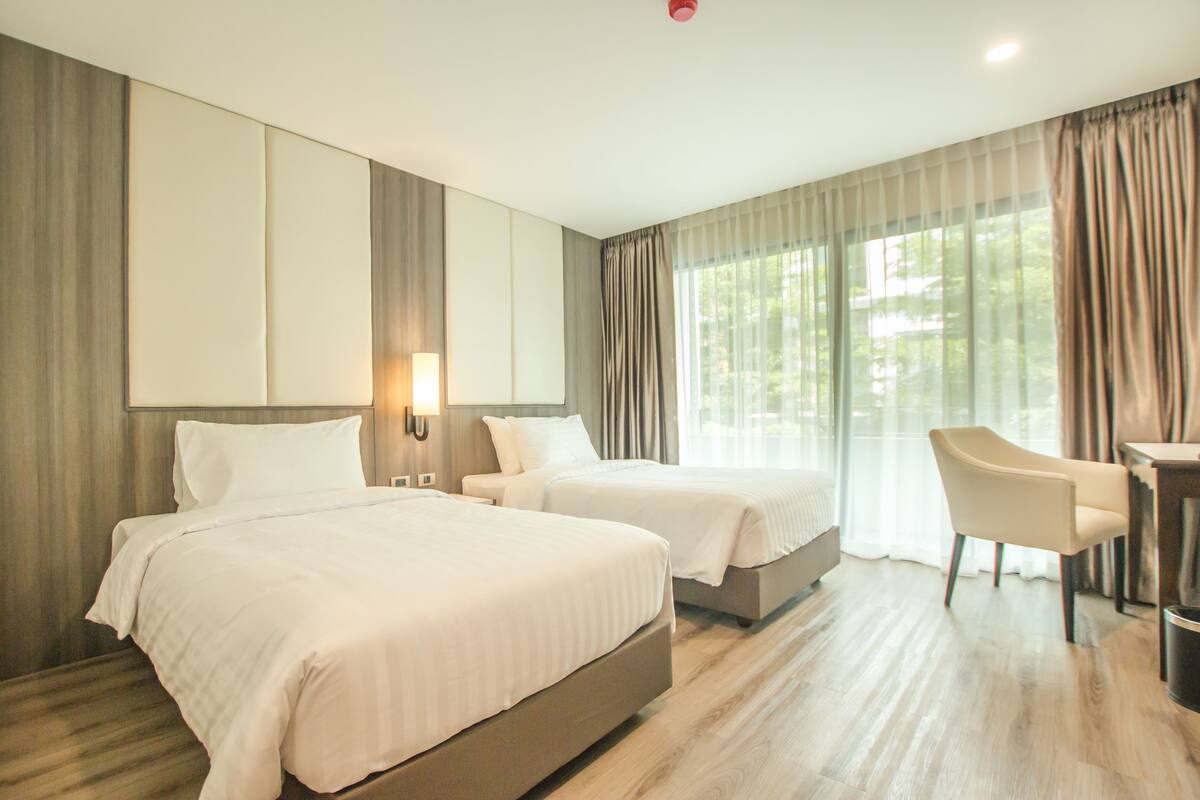 A hotel room with two beds, a desk, and a chair.