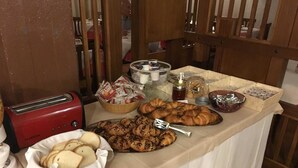 Una mesa de buffet con diferentes opciones de comida, como pan, pasteles y salsas.