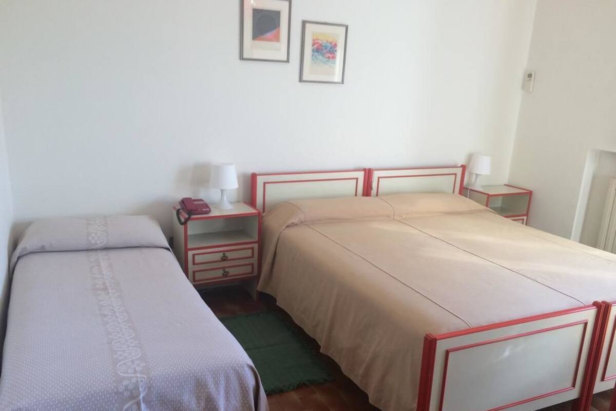 Une chambre avec deux lits simples, une table de chevet avec une lampe et un tapis vert.