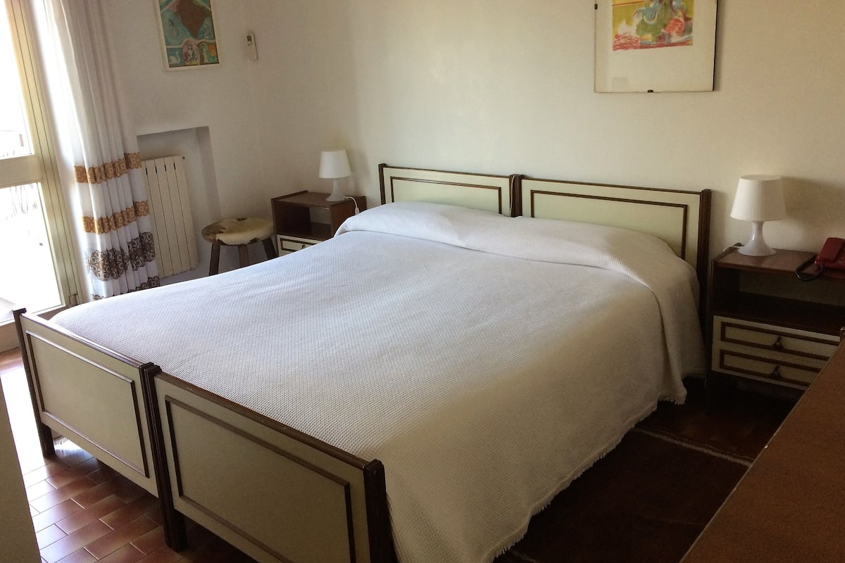 Un lit bien fait dans une chambre avec une tête de lit en bois, une table de chevet avec une lampe et un tableau accroché au mur.