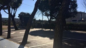 Un estacionamiento con árboles y un edificio al fondo.