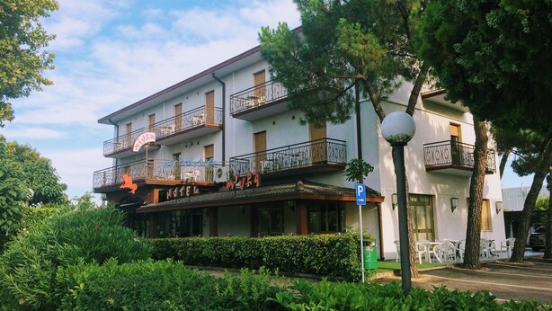 Un hotel de dos pisos con balcones, un restaurante en la planta baja y un letrero de estacionamiento.