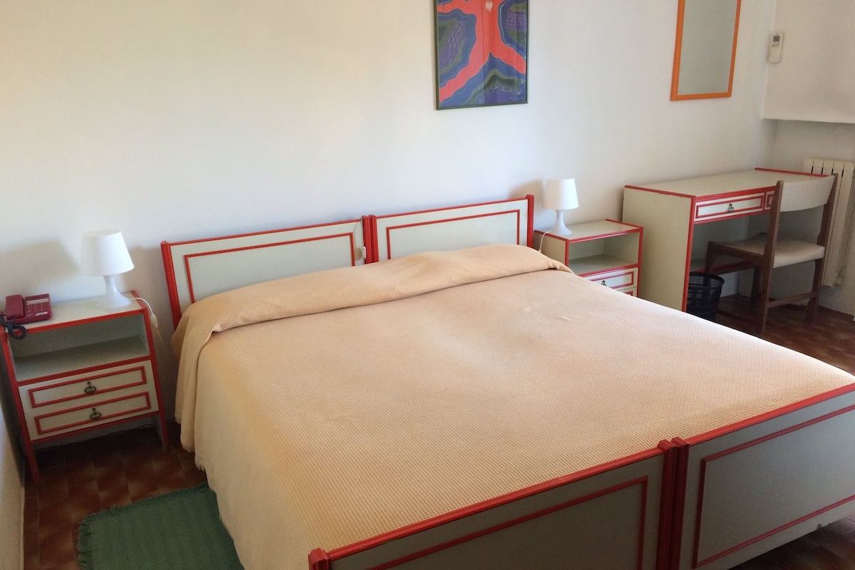 Une chambre à coucher avec un lit, des tables de chevet, un bureau et une chaise.