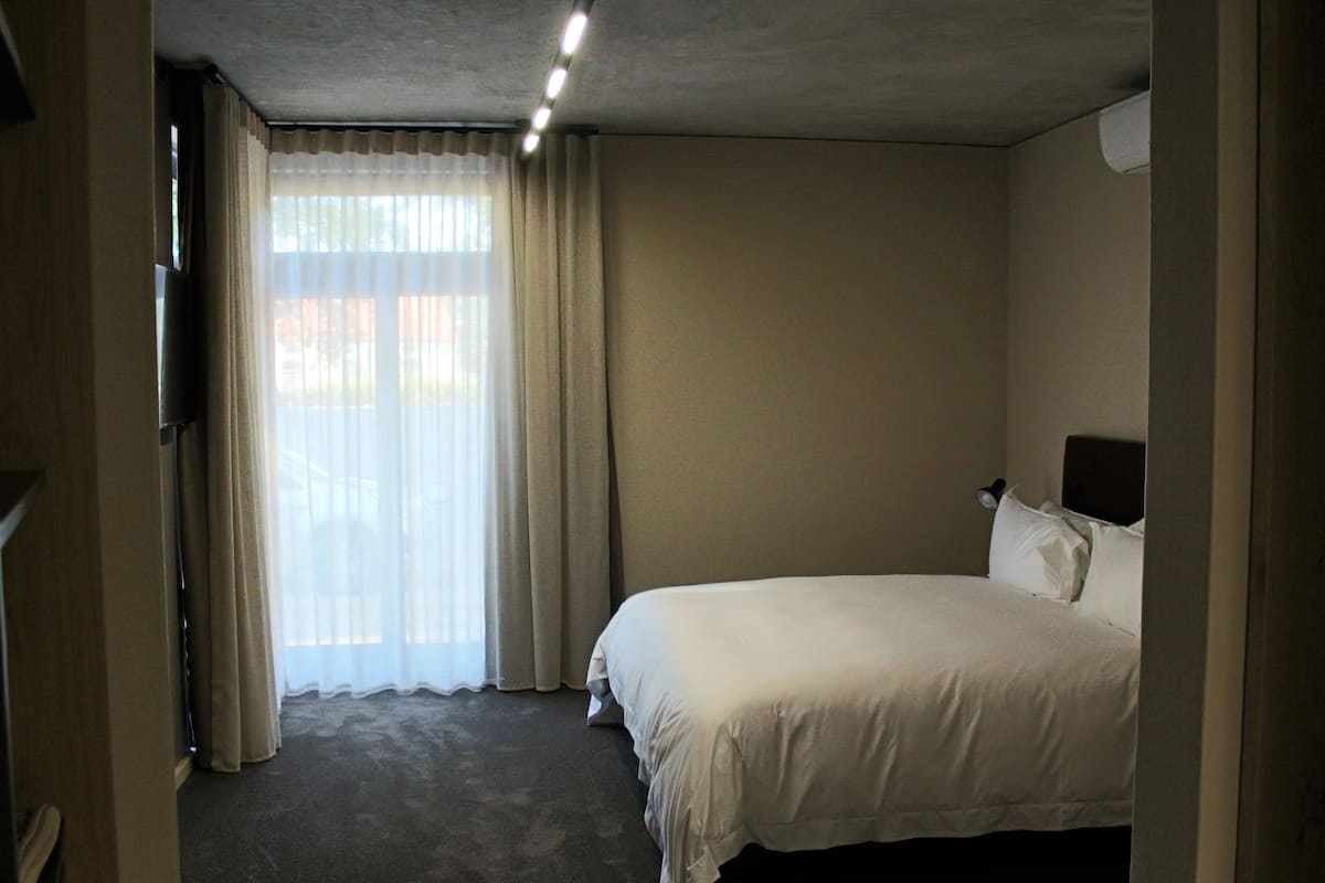 A hotel room with a bed, a television, and a window with curtains.