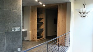 Un intérieur moderne avec une armoire en bois, une rambarde en métal et un lustre.