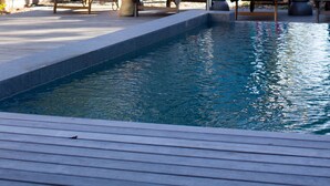 Un espace piscine avec des chaises longues et un coin salon abrité.