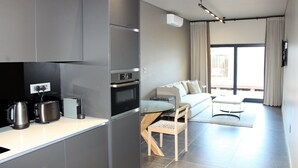 Une cuisine moderne dotée d’un four encastré et d’un coin repas avec une table en verre et un canapé.