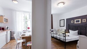 Ein kleines Zimmer mit Bett, Nachttisch und einer kleinen Küchenzeile.
