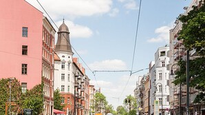 Eine Straße mit Gebäuden, darunter ein markantes, rotes Gebäude und ein weißes Gebäude mit einem Turm.