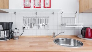 Eine moderne Küche mit Spüle aus Edelstahl, einer Kaffeemaschine und einem Wasserkocher.