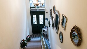A staircase with a black door, a white wall with multiple mirrors, and a chandelier.