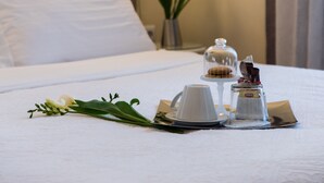 A neatly made bed with a blue headboard, a bedside table with a lamp, and a small vase with flowers.