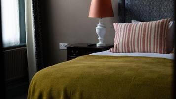 A bed with a dark headboard, a bedside lamp, and a striped pillow.
