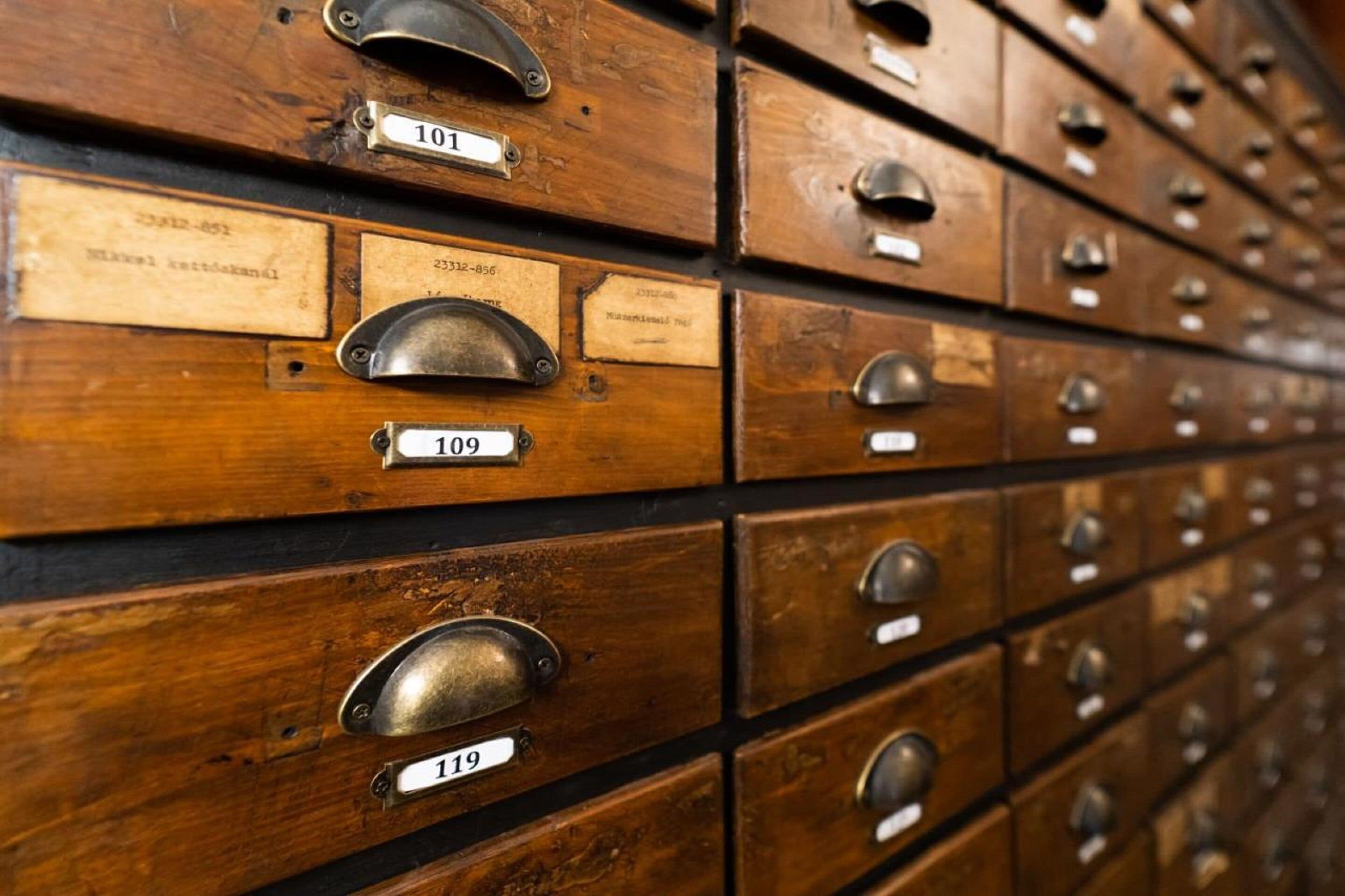 A row of wooden filing cabinets with metal handles and numbered labels.