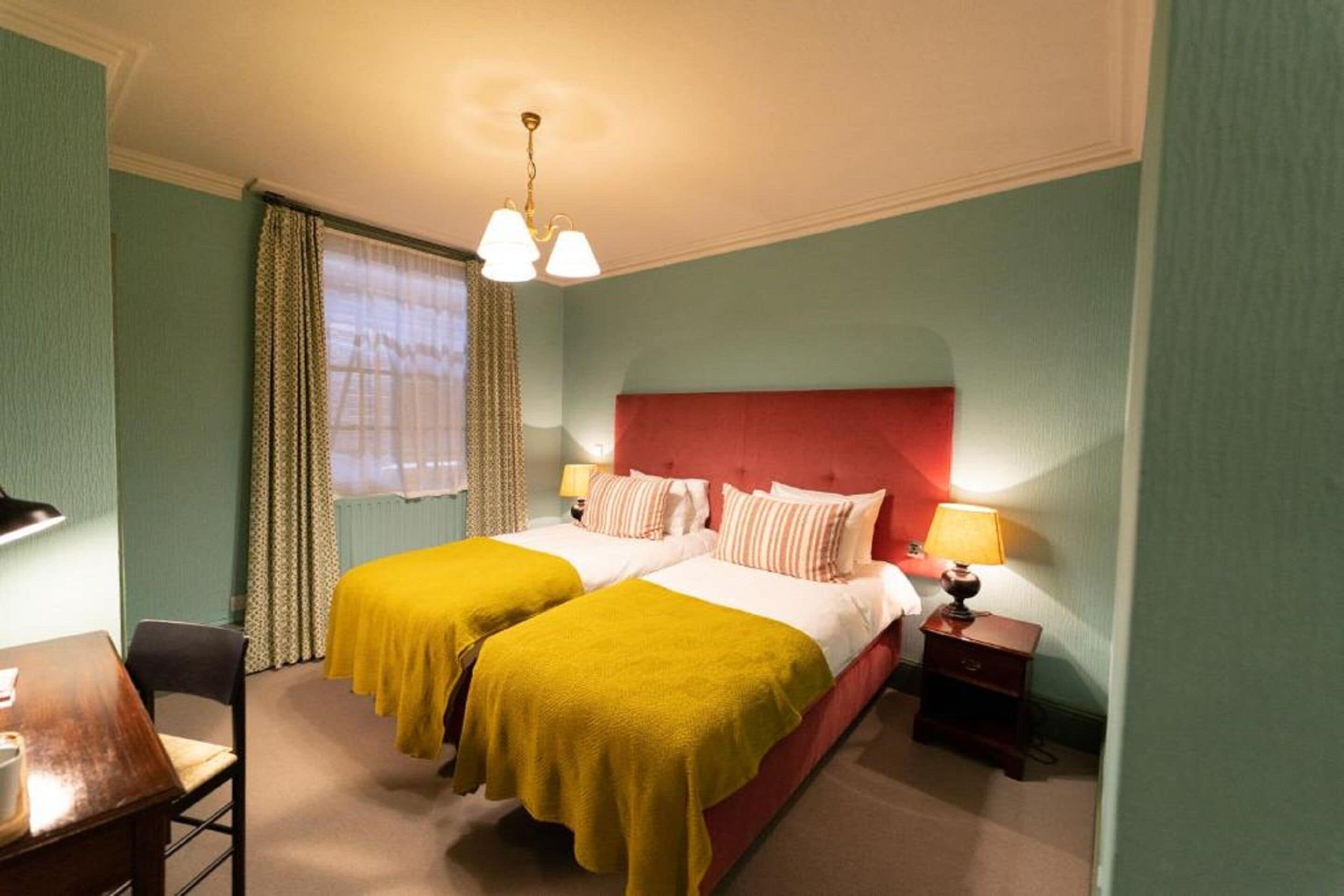 A hotel room with two beds, a desk, and a chair.